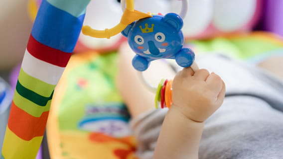 baby arm grabbing plastic bear mobile toy above