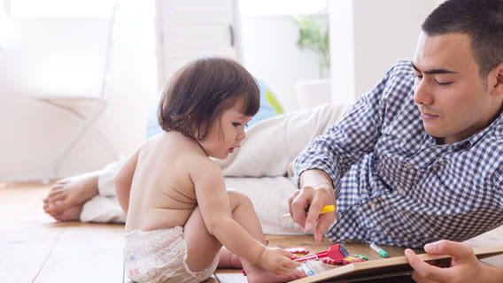 dad and baby on floor playing with mini chalk board