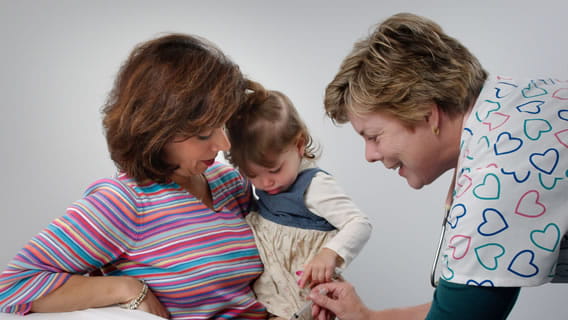 mom holding infant as nurse gives baby a shot in the leg