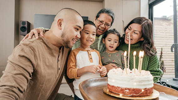 mom, dad, grandma, sister, and brother around cake waiting for brother to blow out candles