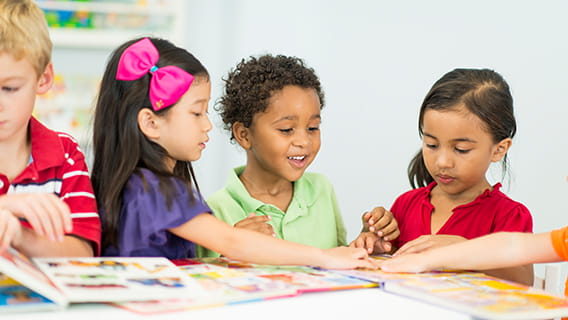 three preschool children looking in books
