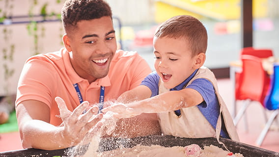 provider and preschooler boy playing with sand