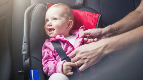 smiling child being strapped in baby seat