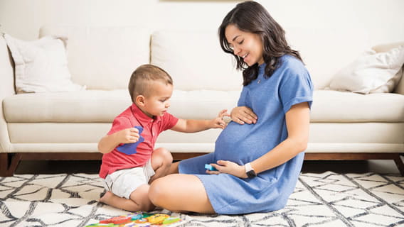 toddler touching expectant mothers belly