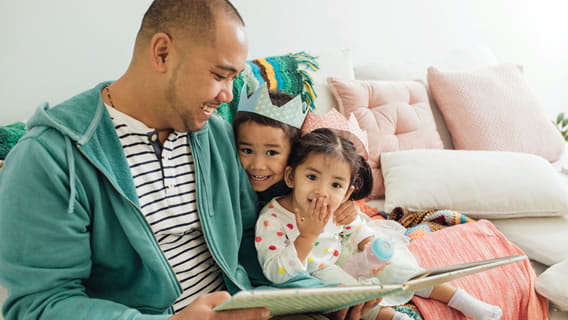 dad reading to two kids with kids wearing paper crowns