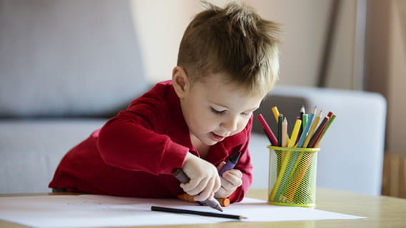 toddler drawing on paper with colored pencils