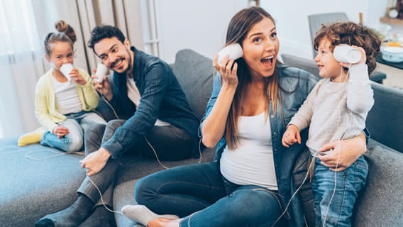 mom, dad and child playing with cup phones