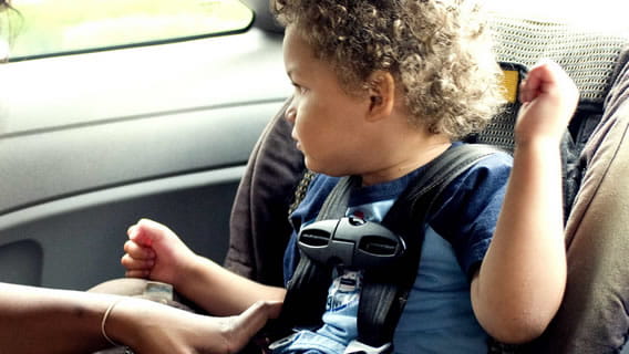 toddler strapped in car seat looking out the car window