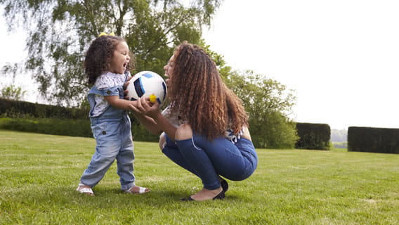 mom and toddler daughter outside playing with soccer ball