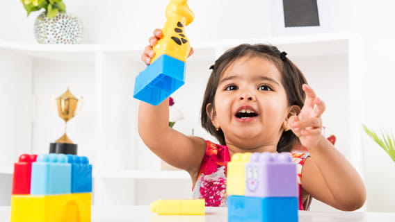 toddler girl holding up Lego style giraffe  block toy 