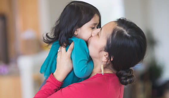 mom holding and kissing daughter