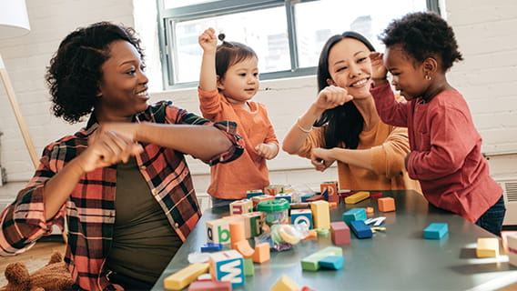 two providers and two toddlers at a table with blocks 