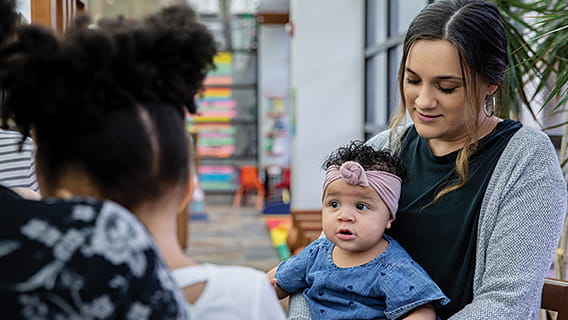 moms in a group setting holding babies