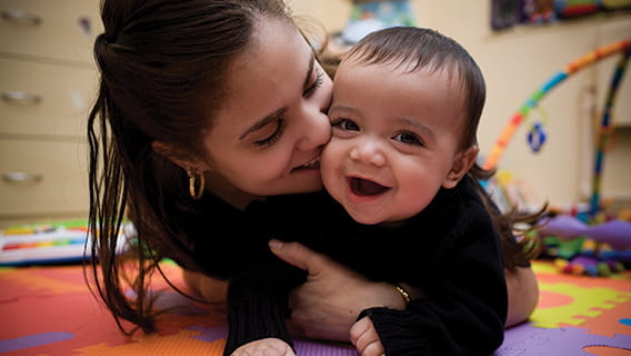 mom kissing smiling infant