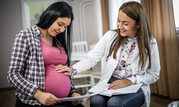 doctor with hand on expectant mother's belly