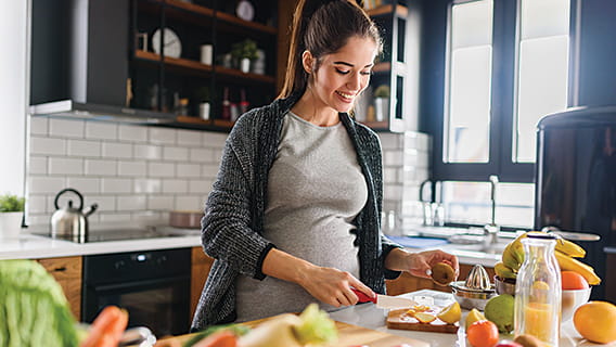 expectant mom in kitchen cutting up fruit