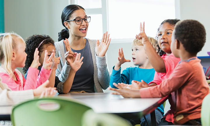 preschool teacher with six children at a table counting on fingers and talking
