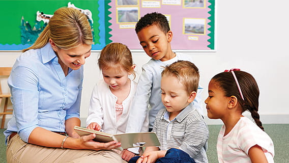 preschool teacher reading to four children