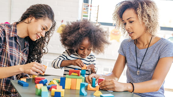 mom toddler and provider sitting at table playing with blocks