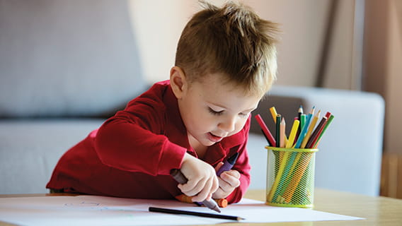 toddler drawing on paper with colored pencils