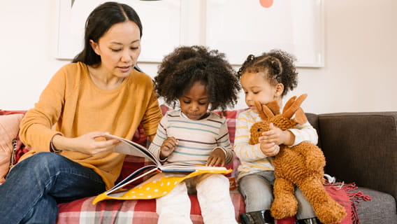 provider on couch reading to two preschoolers