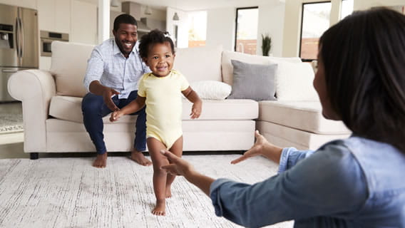 toddler walking from father to mother