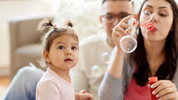 parents blowing bubbles and child watching