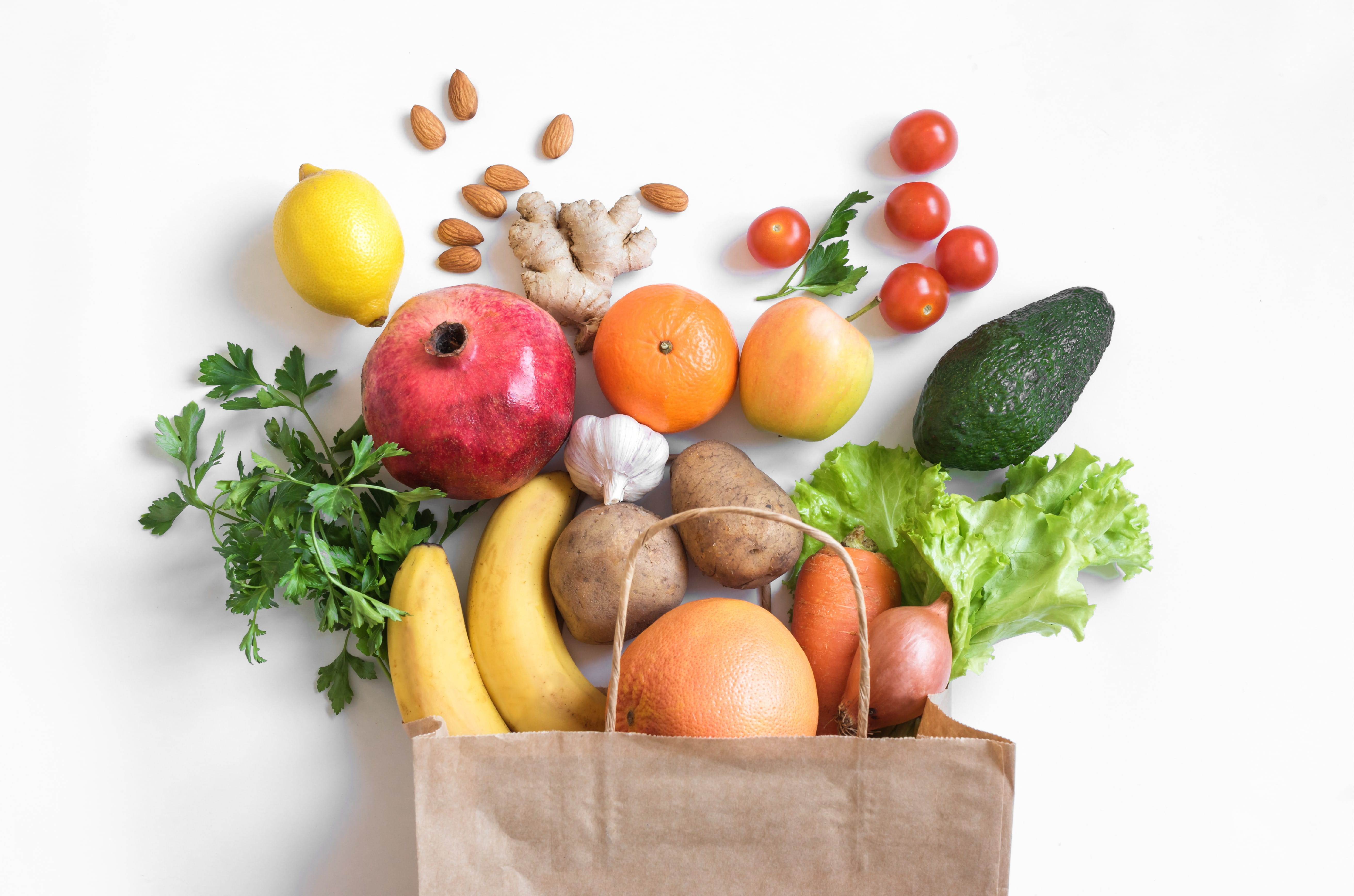 Paper grocery bag spilling out fresh fruits and vegetables