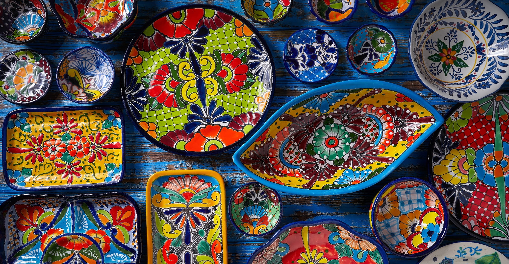 Image of colorfully painted pottery including cups, differently shaped plates, and bowls.