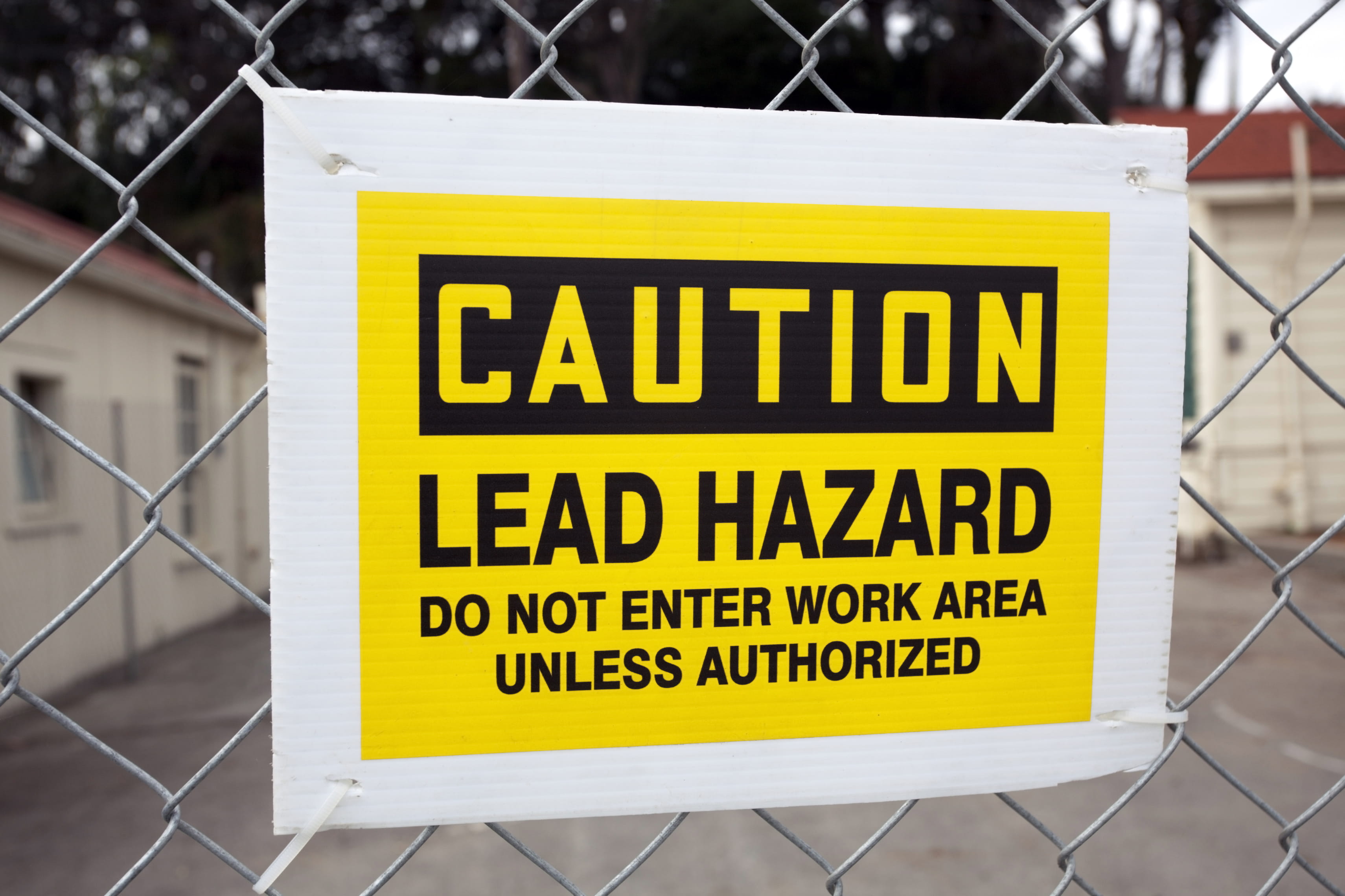 Caution lead hazard do not enter work area unless authorized sign posted on chain fence