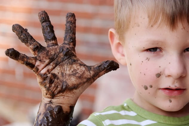 Young boy holding up dirt covered hand