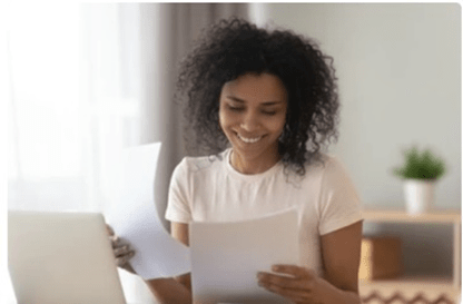 smiling woman holding two papers 
