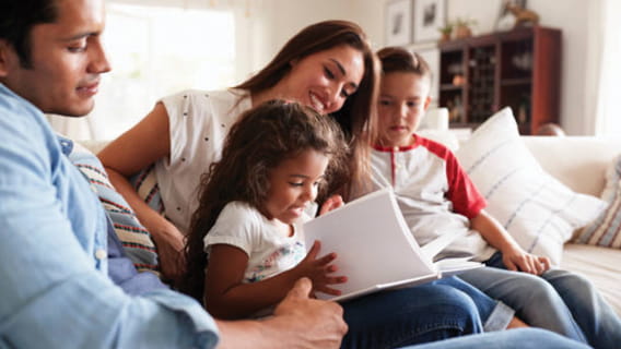 Mother and father on the couch reading to son and daughter