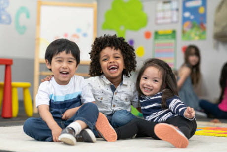 3 kids sitting on floor laughing