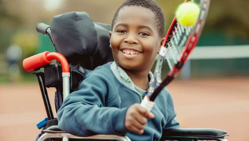 boy in wheelchair hitting tennis ball