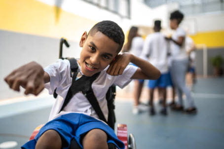 boy in wheelchair with one arm outreached