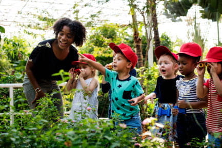 group of kids in a greenhouse with teacher