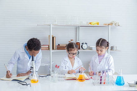 three kids in lab coats doing science