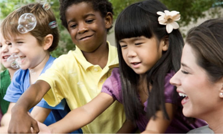 child care provider outside playing with 5 children