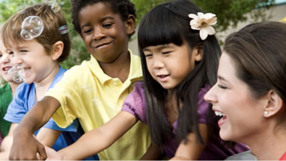 Provider outside with children playing together