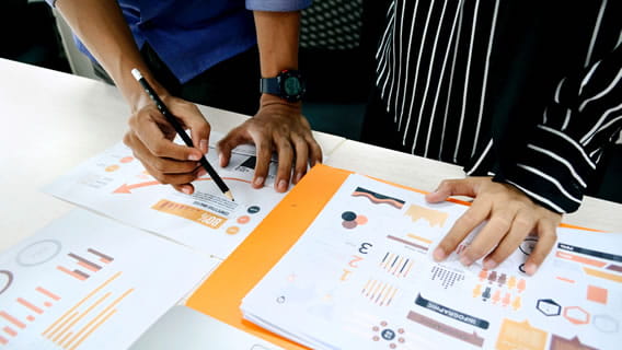 two people pouring over reports and infographics