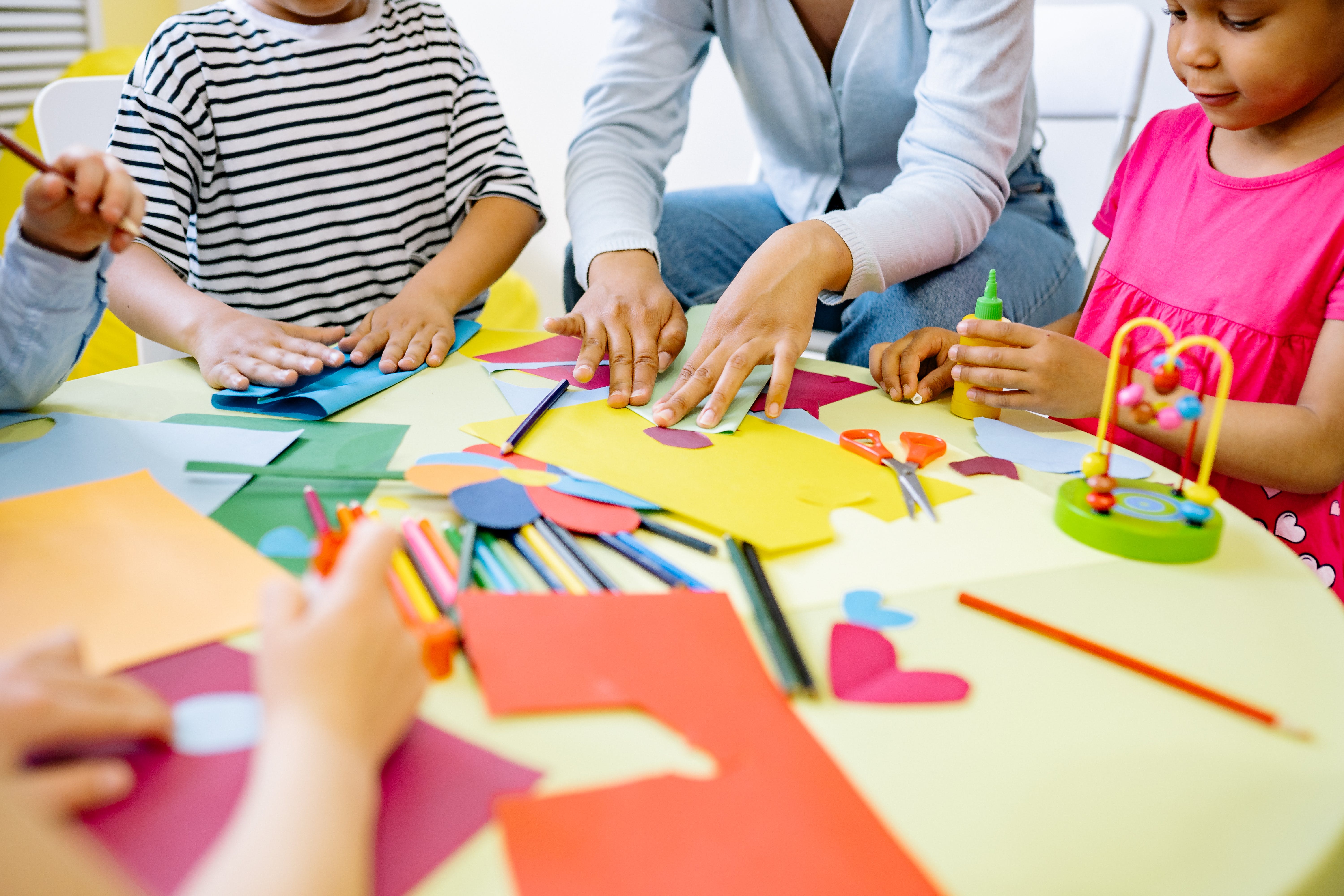 A group of students sitting on a table doing crafts.