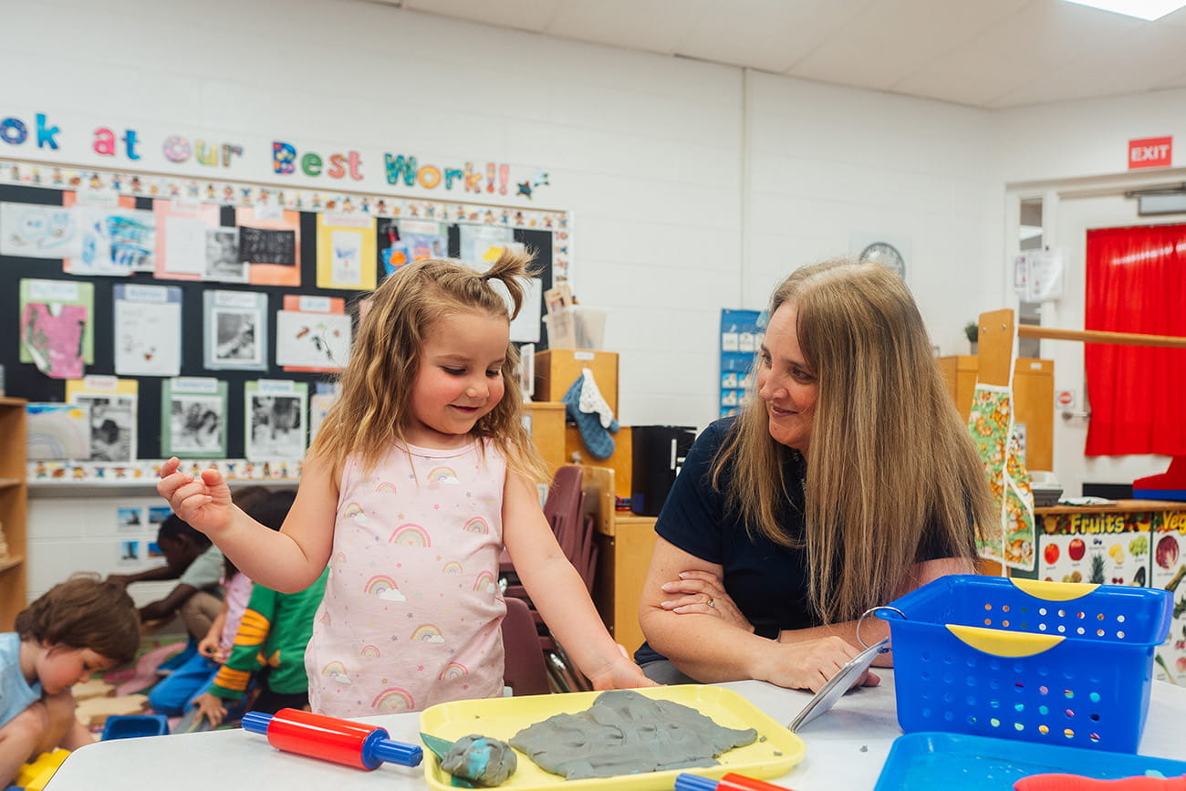 A close up of a student and teacher in a preschool classroom setting