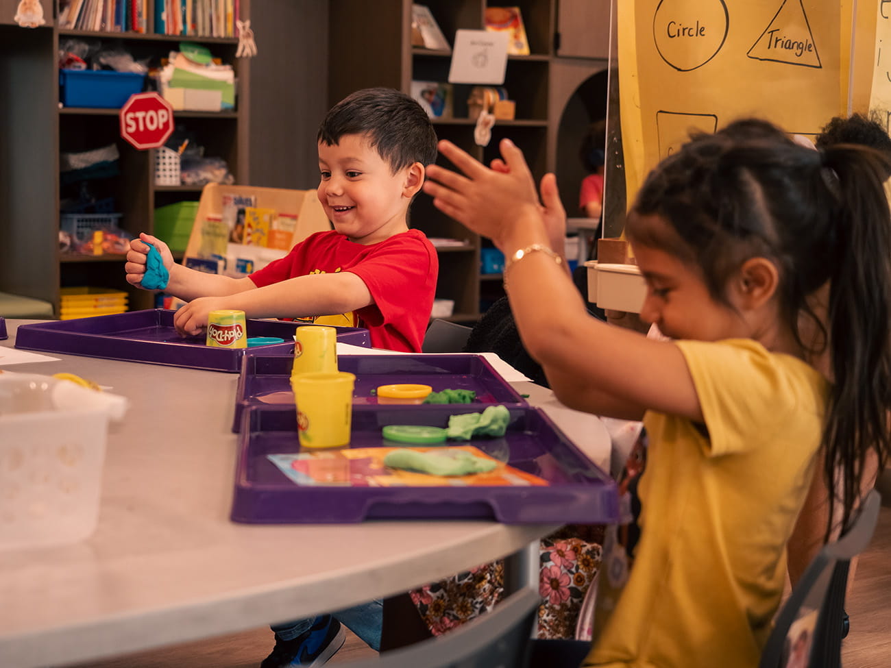Children playing with toys at a table in a preschool classroom