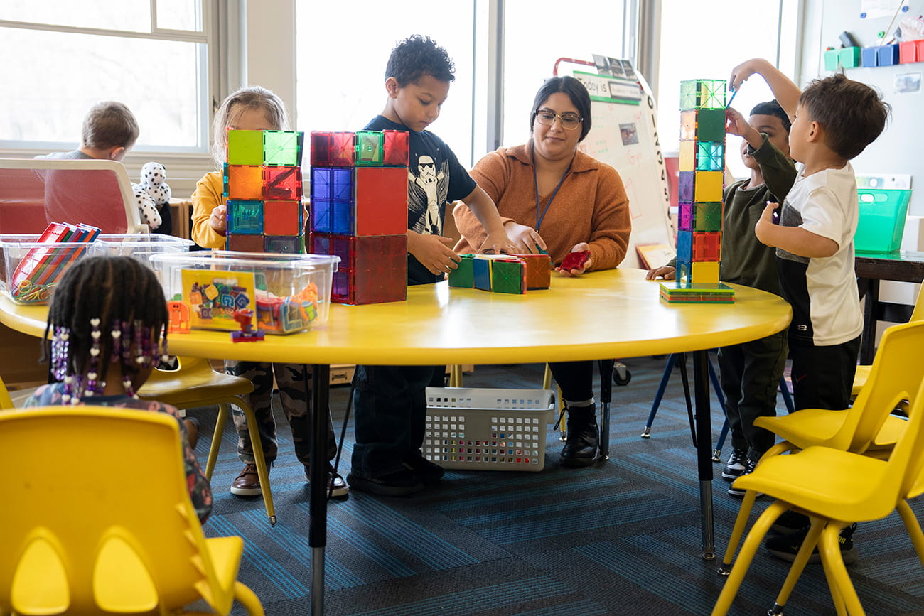 Preschoolers and a teacher a table in a classroom setting