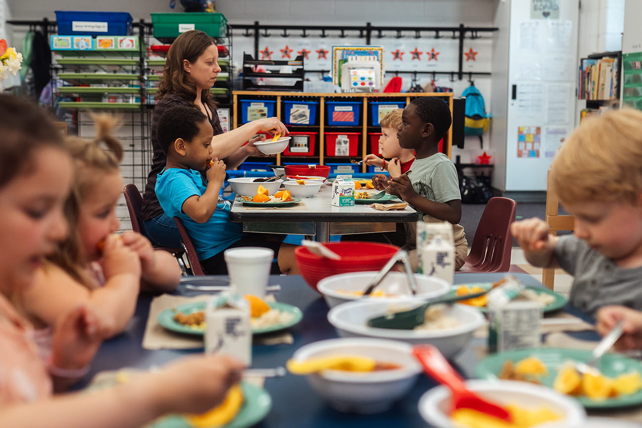 Preschool students eating lunch together at tables