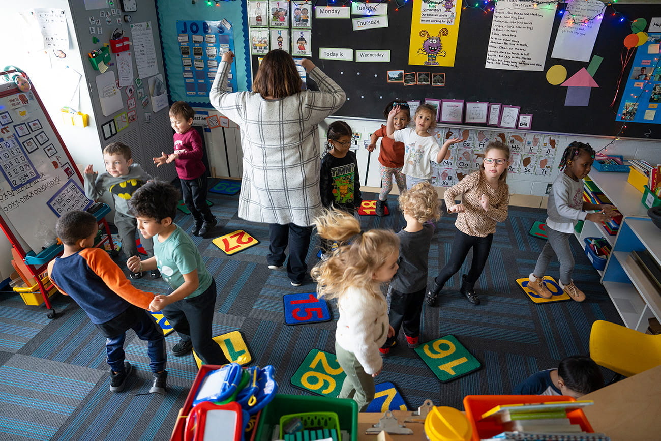 A teacher and students dancing in a preschool classroom