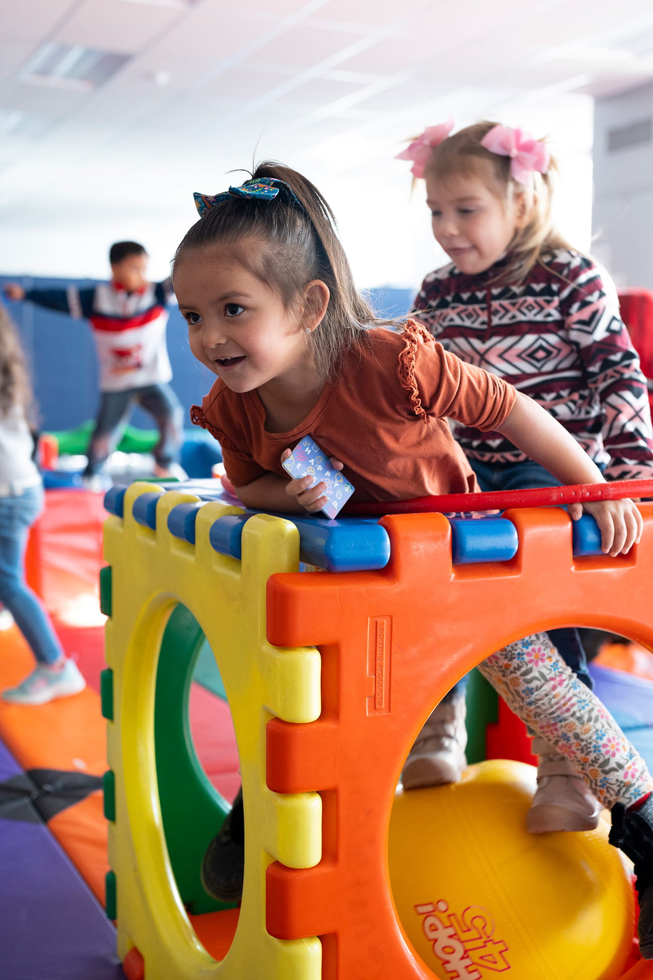 Children climbing on plastic play equipment indoors in a preschool setting