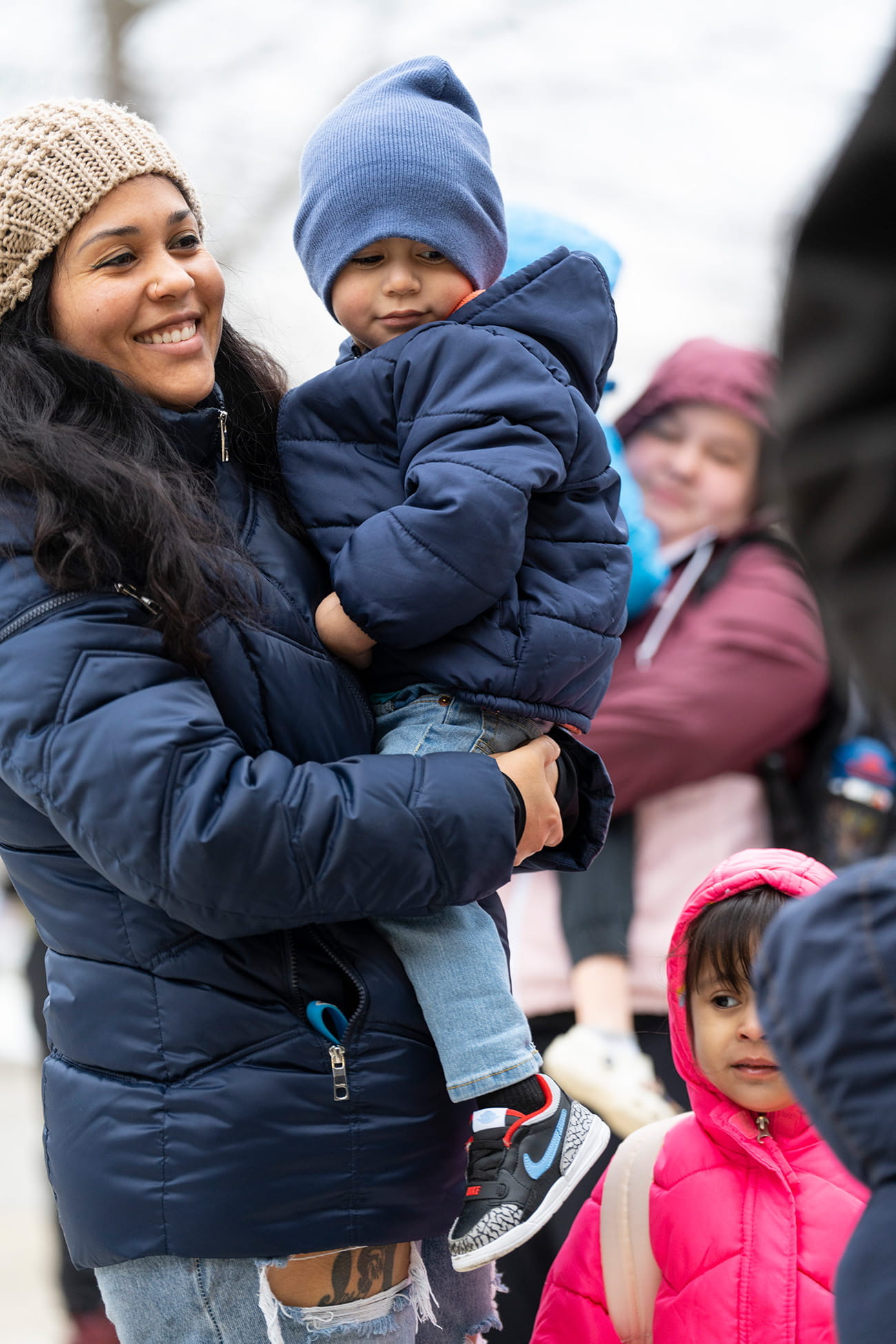 An adult holding a child outdoors and smiling
