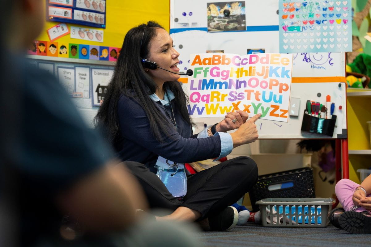 A teacher reading to a group of students on the carpet